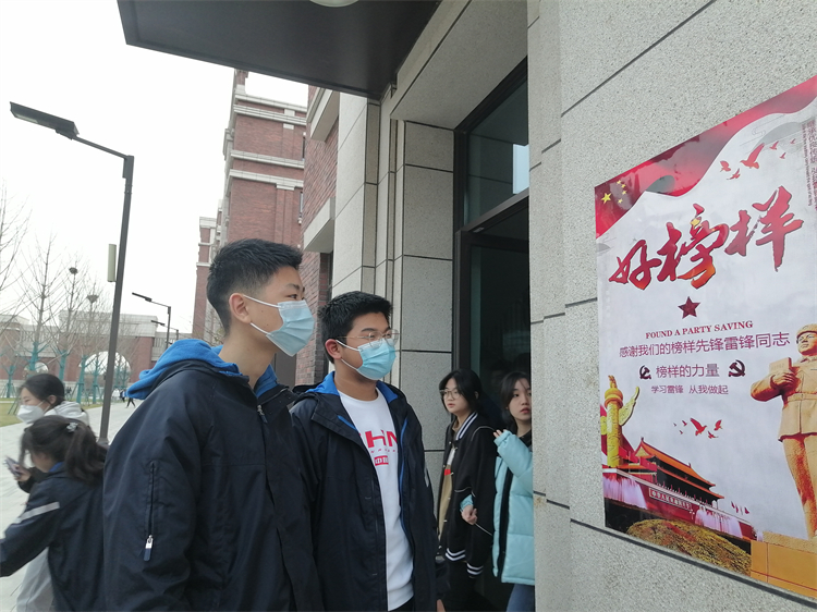 学生课间观看学雷锋主题海报.jpg